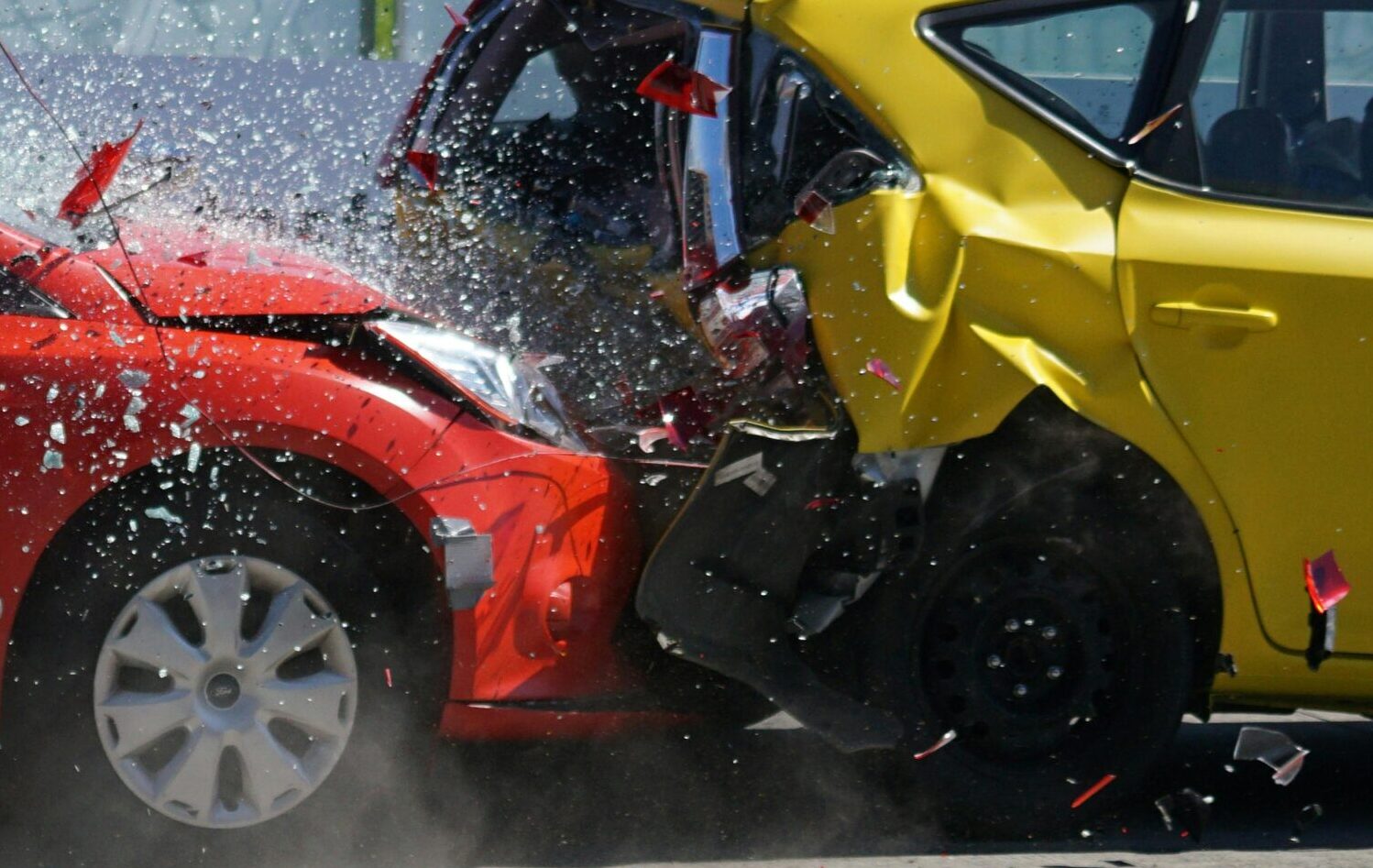 Red and yellow cars shown in a head-on collision during a crash test for safety evaluation.
