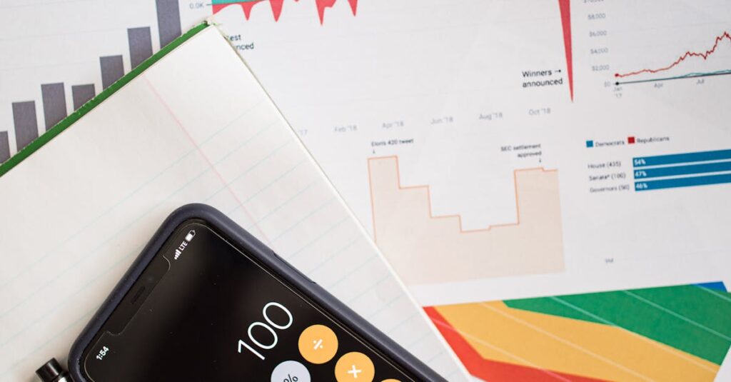 Top view of financial reports with a calculator app open on a smartphone.